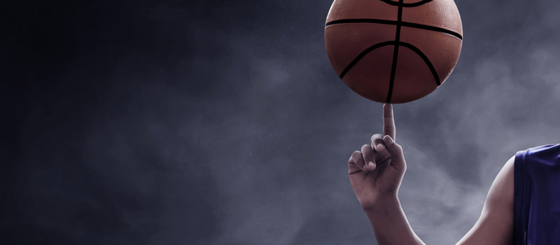 Jogador equilibrando bola de basquete no dedo indicador