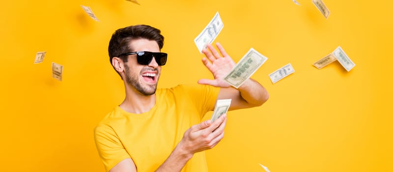 Homem de óculos jogando notas de dinheiro para cima